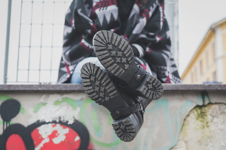 Detail of a young woman with biker boots posing in the city streets