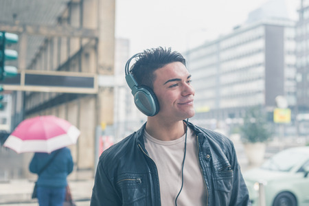 Young handsome man with headphones listening to music in the city streetsの写真素材