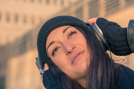 Beautiful young woman with headphones listening to music in the city streetsの写真素材