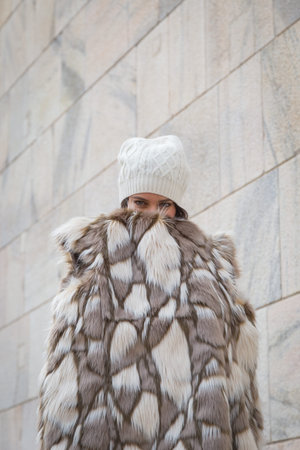 Beautiful young woman wearing ecological fur poses in the city streets - Concept of cruelty free...