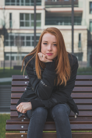 Beautiful young redhead girl posing in the city streets.  の写真素材