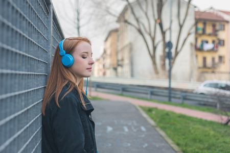 Beautiful young redhead girl posing in the city streetsの写真素材