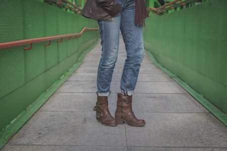 Detail of a young woman with biker boots posing on a bridgeの写真素材