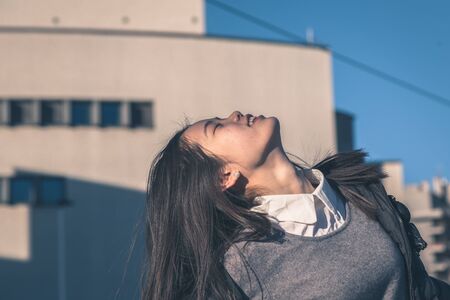 Young beautiful Chinese girl with long hair posing in the city streetsの写真素材