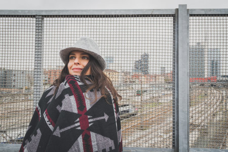 Beautiful young brunette with hat posing in the city streets