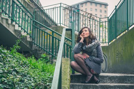 Beautiful young brunette with long hair posing in an urban contextの写真素材