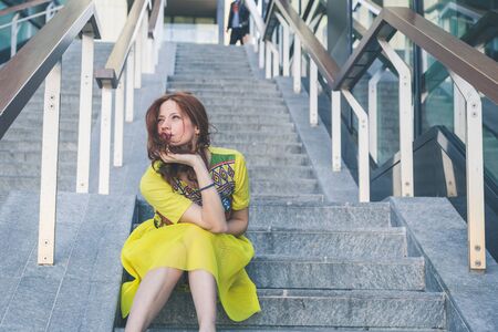Beautiful redhead girl with long hair and blue eyes posing in an urban contextの写真素材