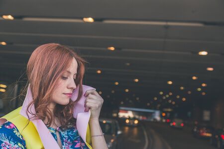 Beautiful redhead girl with long hair and blue eyes posing in an urban contextの写真素材