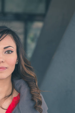 Beautiful young brunette with long hair posing in an urban contextの写真素材