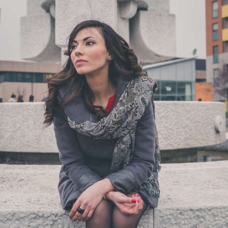 Beautiful young brunette with long hair posing in an urban contextの写真素材