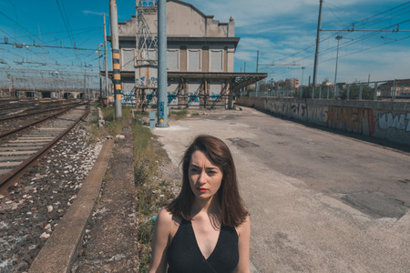 Beautiful young brunette with long hair posing along railroad tracksの写真素材