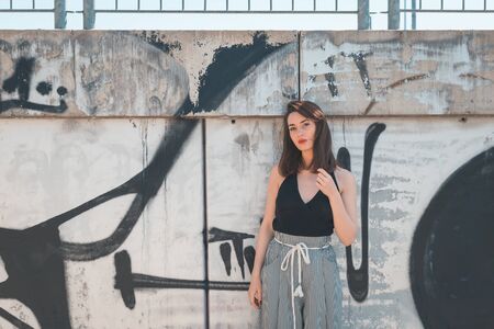 Beautiful young brunette with long hair posing in an industrial areaの写真素材