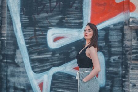 Beautiful young brunette with long hair posing in an industrial areaの写真素材