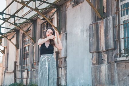 Beautiful young brunette with long hair posing in an industrial areaの写真素材