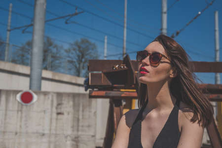 Beautiful young brunette with long hair posing along railroad tracksの写真素材