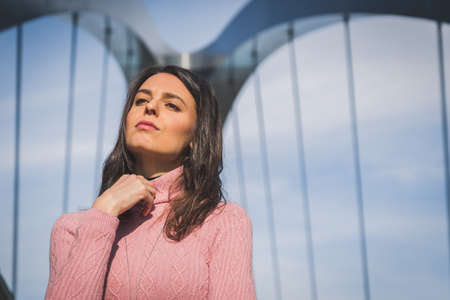 Beautiful young brunette with long hair posing on a bridgeの写真素材