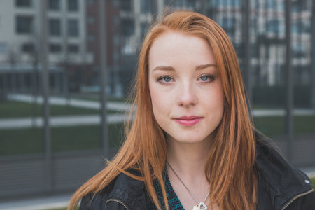 Portrait of a beautiful young redhead girl posing in the city streets