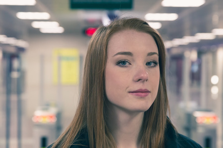 Beautiful young redhead girl posing in a metro stationの写真素材