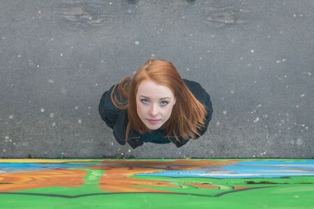 Top view of a beautiful young redhead girl posing in the city streetsの写真素材