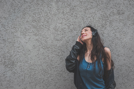 Beautiful girl with headphones listening to music in the city streetsの写真素材