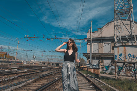Beautiful young brunette with long hair posing along railroad tracks