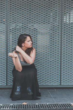 Beautiful young curvy girl in tank top smoking a cigarette in an urban contextの写真素材