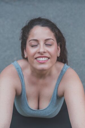 Portrait of a beautiful young curvy girl in tank top posing in an urban contextの写真素材