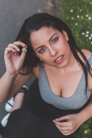 Beautiful young curvy girl in tank top putting a daisy in her hairの写真素材