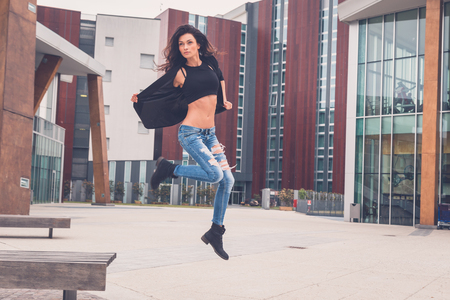 Gorgeous young brunette in jeans jumping from a benchの写真素材