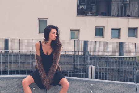 Gorgeous young brunette in black dress posing in an urban contextの写真素材