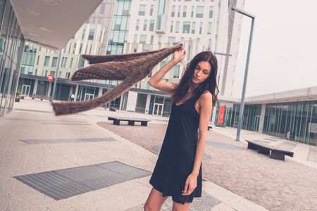 Gorgeous young brunette in black dress posing in an urban contextの写真素材