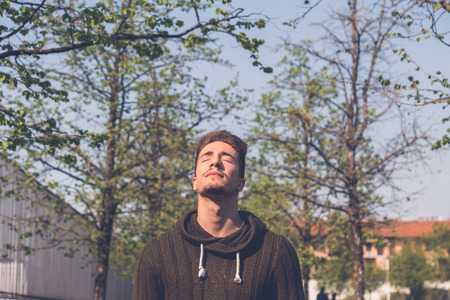 Young handsome man with short hair posing in an urban contextの写真素材