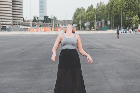 Beautiful young curvy girl in tank top posing in an urban contextの写真素材