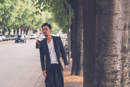 Young handsome Asian model dressed in black posing in the city streetsの写真素材