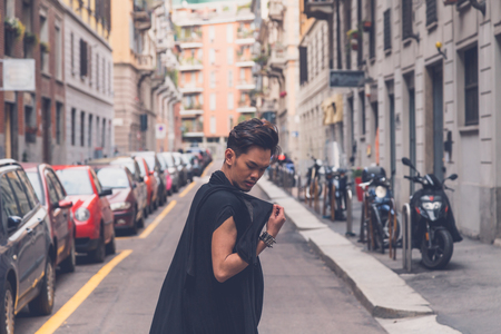 Young handsome Asian model dressed in black tunic posing in the city streetsの写真素材