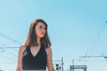 Beautiful young brunette with long hair posing along railroad tracksの写真素材