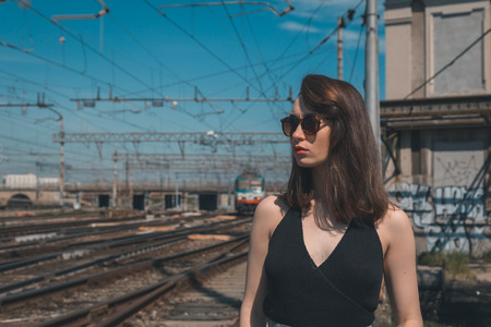 Beautiful young brunette with long hair posing along railroad tracksの写真素材