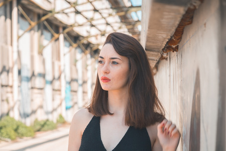 Beautiful young brunette with long hair posing in an industrial areaの写真素材
