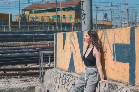 Beautiful young brunette with long hair posing in an industrial areaの写真素材