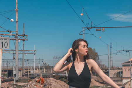 Beautiful young brunette with long hair posing along railroad tracksの写真素材