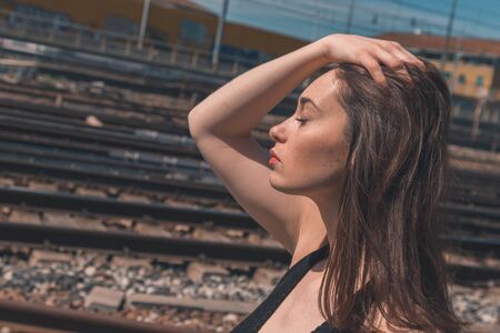 Beautiful young brunette with long hair posing along railroad tracksの写真素材