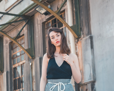 Beautiful young brunette with long hair posing in an industrial areaの写真素材