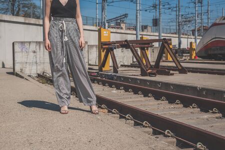 Beautiful young brunette with long hair posing along railroad tracksの写真素材