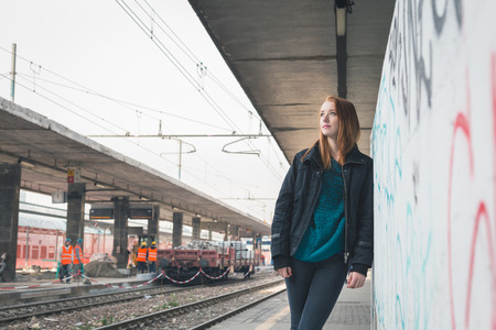 Beautiful young redhead girl posing in a railroad stationの写真素材