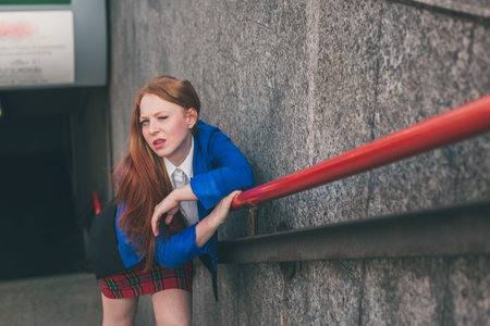 Beautiful redhead girl in blue jacket posing in an urban context