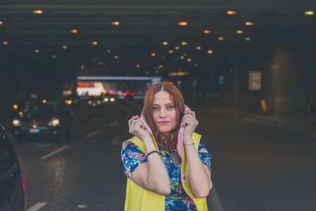 Beautiful redhead girl with long hair and blue eyes posing in an urban contextの写真素材