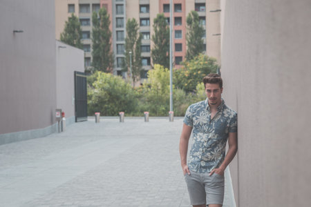 Young handsome man with short hair wearing a short sleeve shirt and posing in an urban context