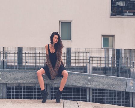 Gorgeous young brunette in black dress posing in an urban contextの写真素材