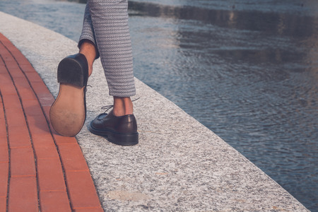 Detail of the shoes of a young handsome Asian model posing by an urban artificial basinの写真素材