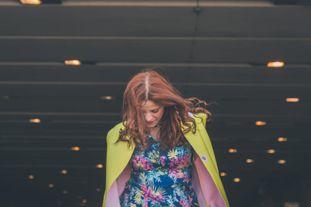 Beautiful redhead girl with long hair and blue eyes posing in an urban context